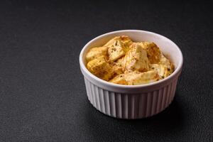 Delicious soft white feta cheese with salt, spices and herbs on a dark concrete background photo