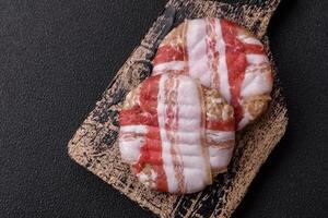 Round minced chicken or pork cutlet wrapped in bacon with salt, spices and herbs photo