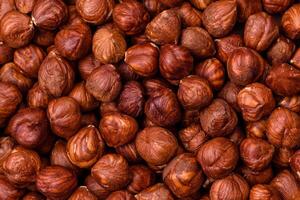 Delicious hazelnut whole, raw, without shell, on a dark concrete background photo