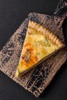 Delicious crispy quiche cut into slices with cheese, broccoli, tomatoes photo