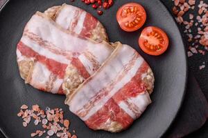 Round minced chicken or pork cutlet wrapped in bacon with salt, spices and herbs photo