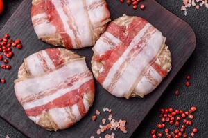 Round minced chicken or pork cutlet wrapped in bacon with salt, spices and herbs photo