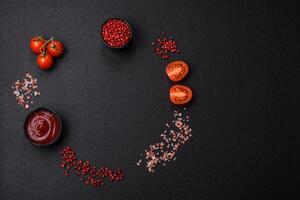 Salt, allspice, cherry tomatoes with copy space on a dark concrete background photo