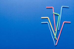 Drinking straws for party on Colored background. Top view of colorful plastic disposable straws for summer cocktails. different straws for juice with copy space photo