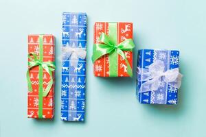 wrapped Christmas or other holiday handmade present in paper with white and green ribbon on blue background. Present box, decoration of gift on colored table, top view photo