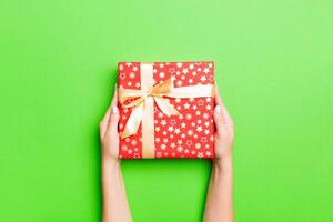 Top view of female hands holding christmas or other holiday handmade present box package in the palms, flat lay table background with copy space photo