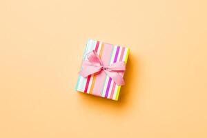 Top view Christmas present box with pink bow on orange background with copy space photo