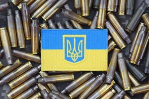 Ukrainian national flag with the coat of arms on the background of military camouflage surrounded by shells. photo