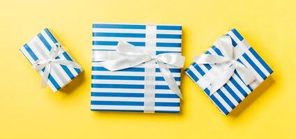 Gift box with White bow in hands for Christmas or New Year day on yellow background, top view photo