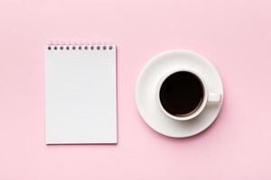 Modern office desk table with notebook and other supplies with cup of coffee. Blank notebook page for you design. Top view, flat lay photo