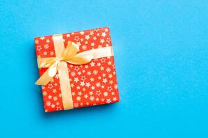 envuelto Navidad o otro fiesta hecho a mano presente en papel con oro cinta en azul antecedentes. presente caja, decoración de regalo en de colores mesa, parte superior ver con Copiar espacio foto