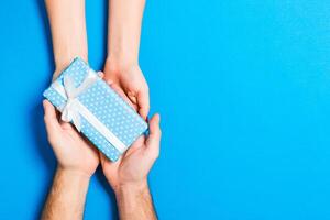 Top view of a man and a woman holding a gift box on colorful background. Love and relationship concept. Copy space photo