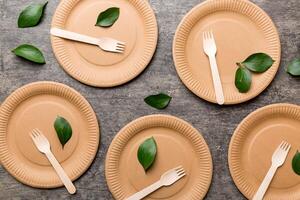 set of empty reusable disposable eco-friendly plates, cups, utensils on light white colored table background. top view. Biodegradable craft dishes. Recycling concept. Close-up photo