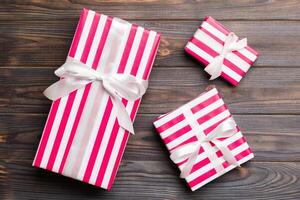 Beautiful gift box with a colored bow on the dark wooden table. Top view banner with copy space for you design photo