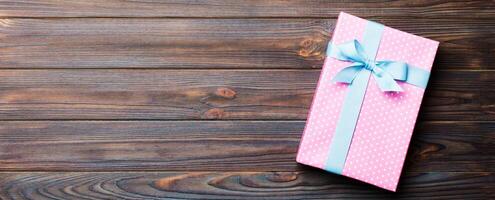 paper gift box with colored ribbon on dark wood background. top view with copy space Christmas holiday concept photo