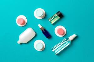 Top view of means for face care bottles and jars of tonic, micellar cleansing water, cream, cotton pads on colored background. Bodycare concept with empty cpace for your ideas photo