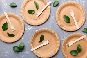 set of empty reusable disposable eco-friendly plates, cups, utensils on light white colored table background. top view. Biodegradable craft dishes. Recycling concept. Close-up photo