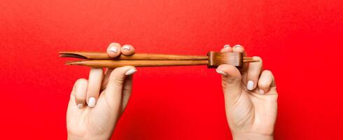 Crop image of two female hands holding chopsticks on red background. Ready to eat concept with copy space photo