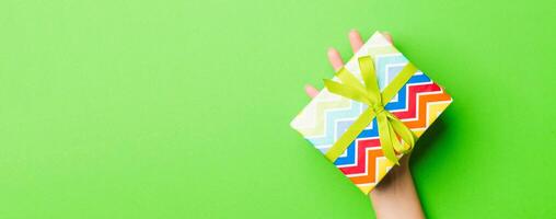 Top view of female hands holding christmas or other holiday handmade present box package in the palms, flat lay table background with copy space photo