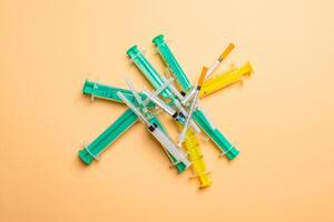 Top view of a heap of syringes and insulin syringes at orange background. Medical injection concept with copy space photo