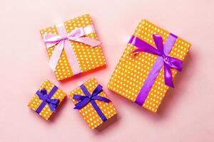 Top view Christmas present box with purple and pink bow on pink background photo