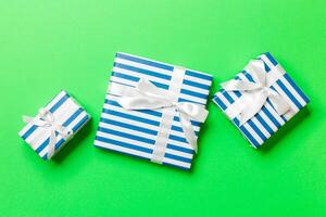 wrapped Christmas or other holiday handmade present in paper with White ribbon on green background. Present box, decoration of gift on colored table, top view photo