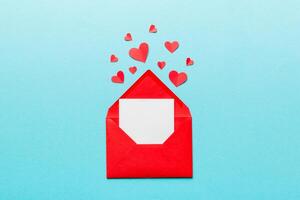 Red paper envelope with empty white card and heart on colored background. top view valentines day concept photo