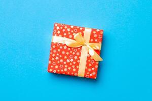 envuelto Navidad o otro fiesta hecho a mano presente en papel con oro cinta en azul antecedentes. presente caja, decoración de regalo en de colores mesa, parte superior ver con Copiar espacio foto