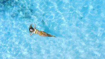 Beautiful woman in bikini relaxing and swim in blue sea. Aerial top down view video