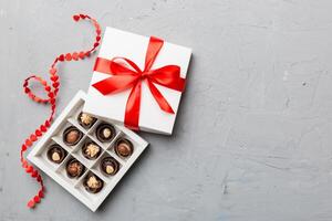 Delicious chocolate pralines in red box for Valentine's Day. Heart shaped box of chocolates top view with copy space photo