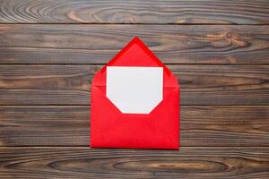 Red paper envelope with empty white card and heart on colored background. top view valentines day concept photo