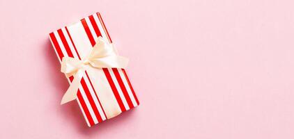 Top view Christmas present box with yellow bow on pink background with copy space photo