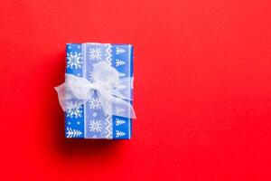 Top view Christmas present box with white bow on red background with copy space photo