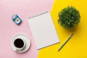 Modern office desk table with notebook and other supplies with cup of coffee. Blank notebook page for you design. Top view, flat lay photo