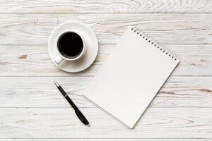 Modern office desk table with notebook and other supplies with cup of coffee. Blank notebook page for you design. Top view, flat lay photo