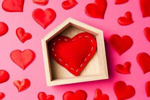 primer plano de corazón rojo en una casa de madera decorada con pequeños corazones sobre fondo colorido. día de San Valentín. concepto de hogar dulce hogar foto