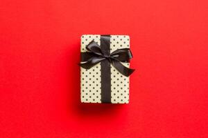 Top view Christmas present box with black bow on red background with copy space photo