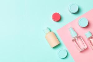 Top view of cosmetic containers, sprays, jars and bottles on pink background. Close-up view with empty space for your design photo