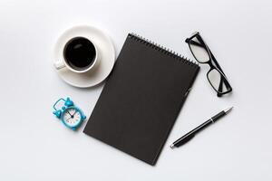 Modern office desk table with notebook and other supplies with cup of coffee. Blank notebook page for you design. Top view, flat lay photo