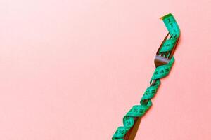 Fork wrapped in measuring tape on pink background with copy space. Top view of proper diet concept photo