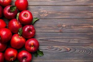 Fresh red apples with green leaves on wooden table. On wooden background. Top view free space for text photo