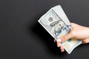 Top view of female hand giving one hundred dollar bills on colorful background. Charity and donation concept with copy space photo