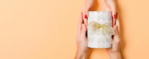 Top view of a man and a woman giving and receiving gift for a holiday on colorful background. Love and relationship concept with copy space photo