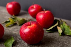Fresh red apples with green leaves on wooden table. On wooden background. Top view free space for text photo
