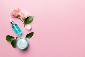 Composition with cosmetic products and beautiful roses on color background. Copy space, flat lay photo