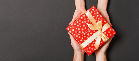 Top view of two people sharing a present on colorful background. Holiday and surprise concept. Copy space photo