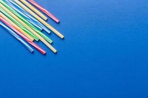 Heap of colorful plastic drinking straws on Colored background, flat lay. Copy Space for text photo