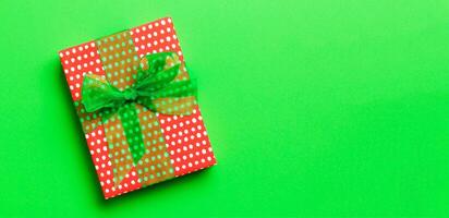 Top view Christmas present box with green bow on green background with copy space photo