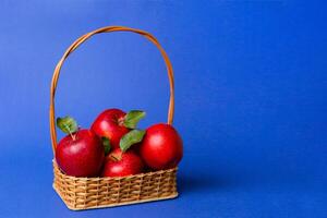 Ripe garden apple fruits with leaves in basket on wooden table. Top view flat lay with copy space photo