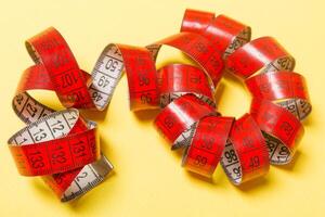 Perspective view of curled measure tape on yellow background. Keeping fit concept photo